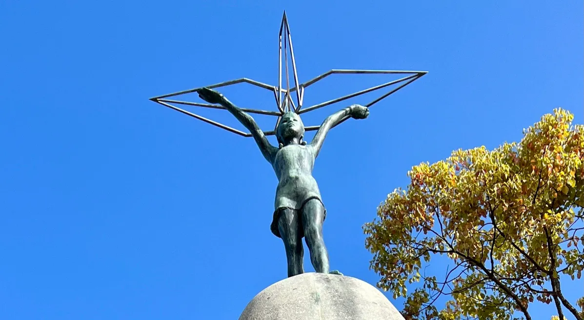 Estatua de bronce de la niña sosteniendo una grulla de papel